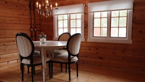 A wooden interior with a dining table and chairs, large windows, and a chandelier. - Velfjord camping & hytter (Brønnøy)