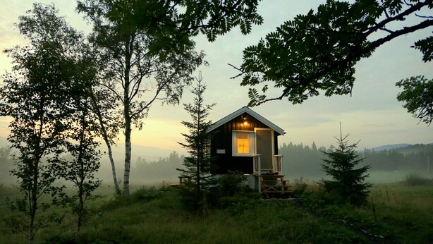 A cabin with a wooden exterior, a porch, and a single visible window. - Velfjord camping & hytter (Brønnøy)