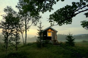 A cabin with a wooden exterior, a porch, and a single visible window. - Velfjord camping & hytter (Brønnøy)