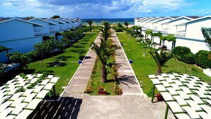 A row of white beachside cottages with a central pathway, palm trees, and a view of the ocean. - Afytos Kazdaglari Akcay (Edremit)