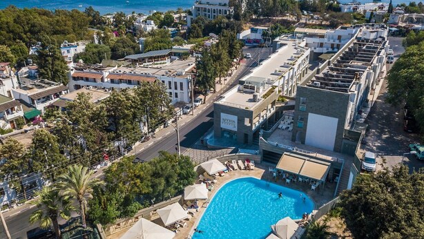 Un hotel con piscina, rodeado de edificios y vistas al mar.