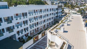 Un hotel de varios pisos con balcones, un patio central y una zona de estacionamiento.