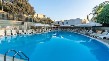 Una piscina al aire libre de temporada, sombrillas, tumbonas