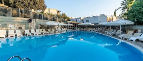 Una piscina al aire libre de temporada, sombrillas