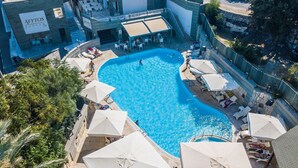 Una gran piscina al aire libre rodeada de sillones de playa y sombrillas, con un edificio con el rótulo "AFYTOS BODRUM" al fondo.