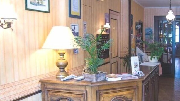 A hallway with wooden paneling, a desk with a lamp, and a potted plant. - Hotel de la Gare (Dol-de-Bretagne)