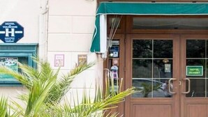 A hotel entrance with a green awning, a sign indicating 'HOTEL TOURISM', and a 'HOTEL OUVERT' sign. - Hotel de la Gare (Dol-de-Bretagne)