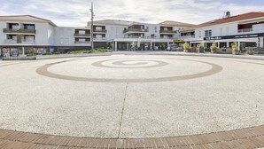 Una piazza pubblica dalla forma circolare, circondata da edifici a più piani con negozi e ristoranti.