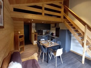 L’intérieur d’un chalet accueillant, avec un coin repas, une cuisine et un escalier en bois.