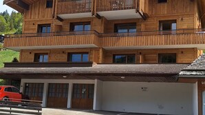 Ein mehrstöckiges Holzgebäude mit Balkonen, einer Garage und einem Parkplatz.