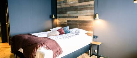A modern bedroom with a wooden headboard, a bed with white linens, and two bedside lamps.