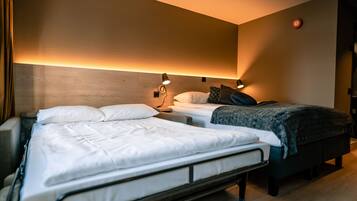 Habitación de hotel con dos camas, cabecero de madera, lámparas de noche y luz empotrada en la pared.