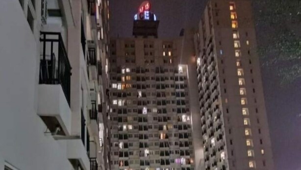 Un immeuble de grande hauteur, doté de nombreux étages, de balcons et d’une enseigne lumineuse au sommet.