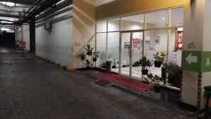 L’entrée d’un hôtel, avec une porte en verre, des plantes en pot et un tapis rouge menant à l’entrée.