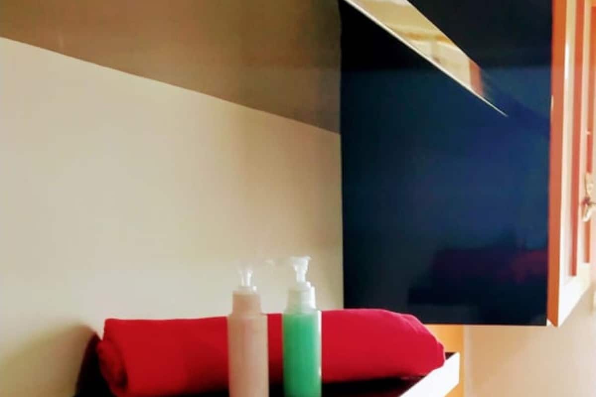 Een badkamer met een spiegel, een wastafel en een plank met toiletartikelen.