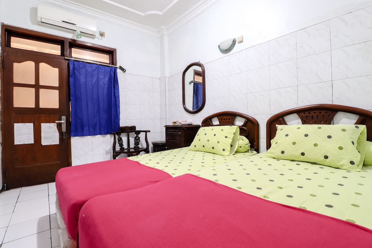 A hotel room with a bed, a wooden wardrobe, a mirror, and a blue curtain.