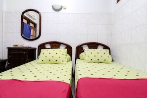 Una habitación con dos camas, un aparador de madera, un espejo y una lámpara fijada a la pared.
