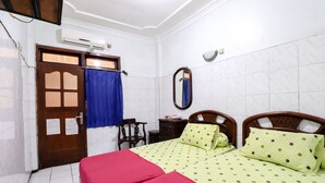 A room with two beds, a wooden door, a mirror, a desk, and a chair. - Hotel Gajah Mada (Surabaya)