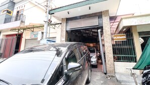 A building with a garage entrance, a sign reading "GAJAHMADADA", and a parked car. - Hotel Gajah Mada (Surabaya)
