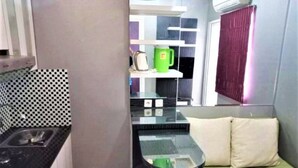 A compact kitchen with a black countertop, a sink, and a green mug on a shelf. - Green Pramuka Apartement By Vici (Jakarta)