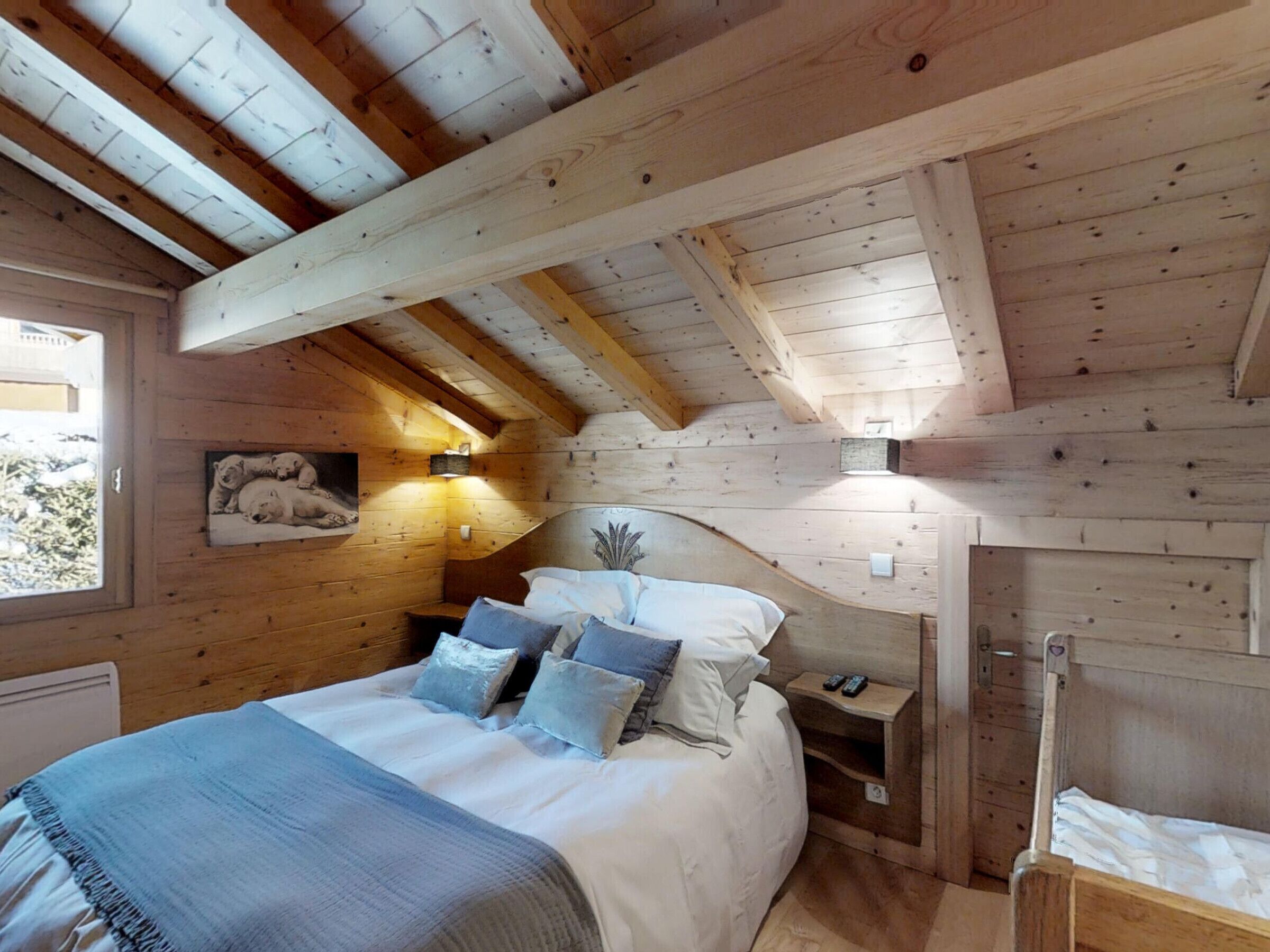 A wooden cabin bedroom with a bed, pillows, a nightstand, and a window.