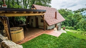 A rustic cabin with a red-tiled roof, wooden exterior, and a stone chimney.