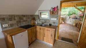 A compact kitchen with a built-in stove, wooden cabinets, and a window overlooking a stone patio.