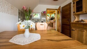 A wooden dining table with a lace doily, a white vase with flowers, and a wooden cabinet.