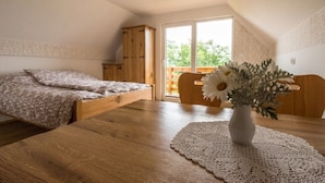 A bedroom with a wooden bed, a wooden table with a vase of flowers, and a view of the outdoors through a sliding door.