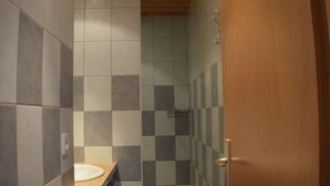 Un baño con puerta de madera, un lavamanos y paredes de azulejos.