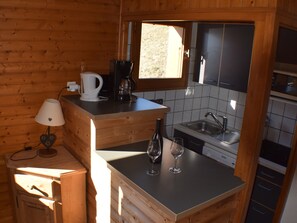 Une cuisine de taille réduite, dotée de meubles en bois, d’un évier et d’une fenêtre qui laisse entrer la lumière naturelle.