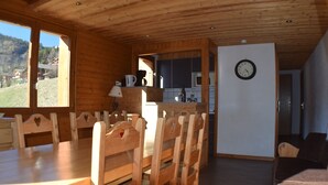Un interior de madera con una mesa de comedor y sillas, una zona de cocina y un espacio de estar con un sofá.