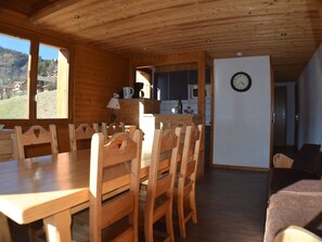 Un intérieur en bois comprenant une table et des chaises, un coin cuisine et un espace de vie avec un canapé.