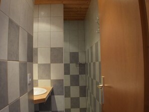 A bathroom with a wooden door, a sink, and tiled walls.