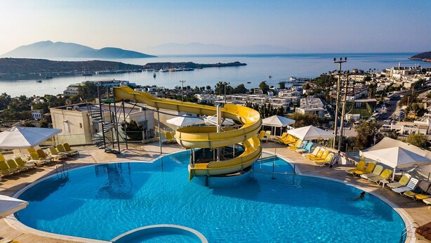 Une grande piscine avec un toboggan, des chaises longues et des parasols.