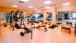 Une salle de sport spacieuse équipée de divers appareils d’exercice, de miroirs et d’un espace d’accueil.