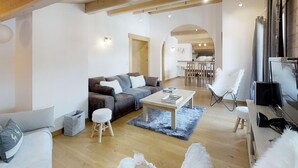 A spacious living area with a wooden ceiling, a sofa, a coffee table, and a dining area in the background. - Cozy apartment for 4 at the foot of the slopes (Le Grand-Bornand)