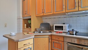 Une cuisine compacte avec des meubles en bois, un four à micro-ondes, une cuisinière et une machine à café.