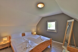 Un dormitorio con una cama de madera, dos mesitas de noche con lámparas, una ventana y un espejo.
