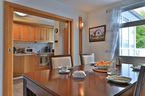 Une cuisine moderne avec des meubles en bois, un four à micro-ondes, une cuisinière et un coin repas avec une table dressée pour deux personnes.