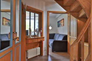 Un couloir avec des portes en bois, un radiateur et un canapé gris.