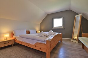 Une chambre à coucher avec un lit en bois, une table de chevet, une commode, un miroir et une fenêtre.