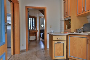 Une cuisine avec des meubles en bois, un plan de travail et une vue sur le salon attenant.