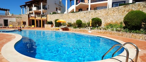 A swimming pool with a stone wall and a tiled deck.
