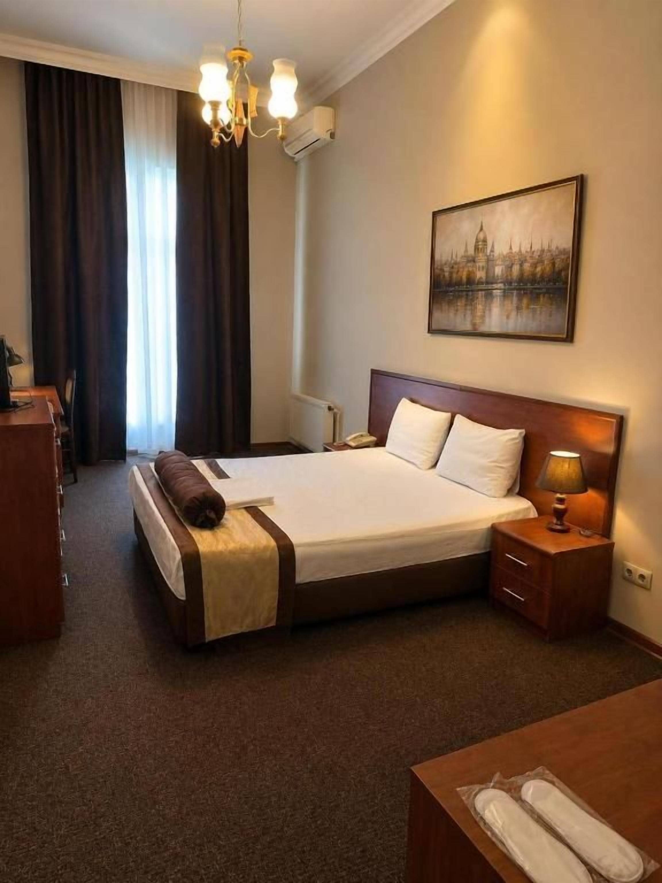 Una camera d'albergo con un letto grande, comodini, una lampada e un quadro appeso al muro.
