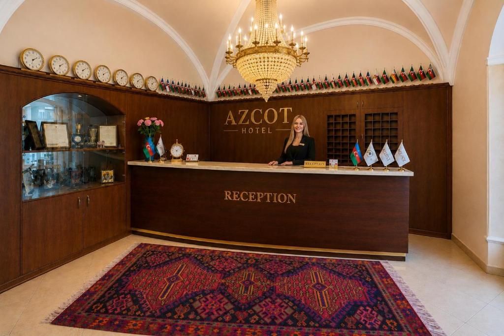 A reception desk with a chandelier, clocks, and flags.