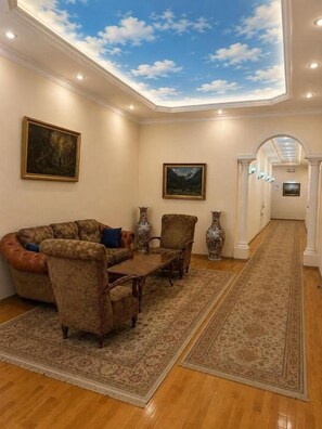 A room with a ceiling mural, a sofa, chairs, a coffee table, and a rug. - Azcot Center Hotel (Baku)
