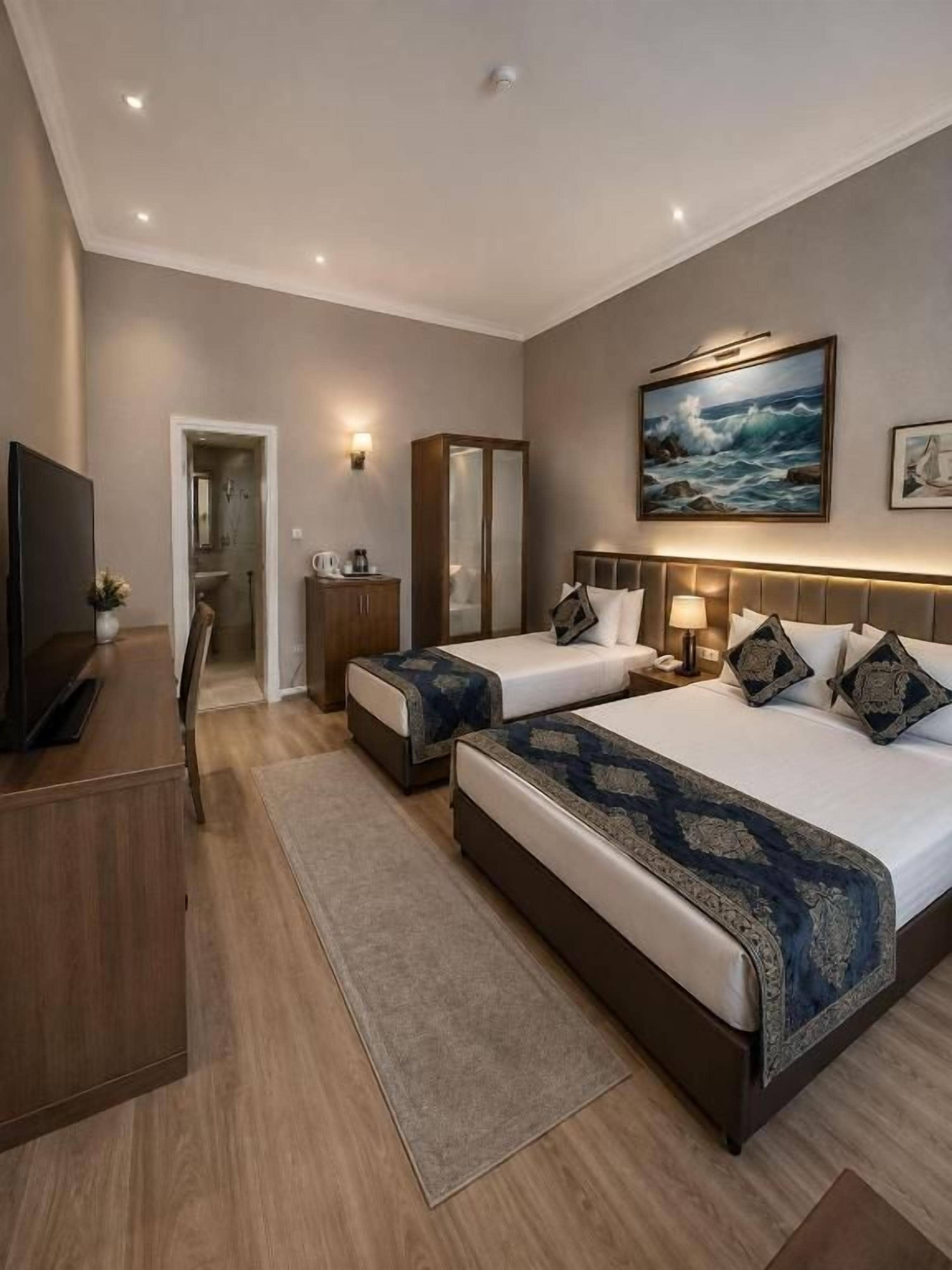 Une chambre d’hôtel avec deux lits, une télévision, une armoire et un tableau au mur.