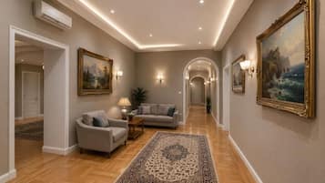 A hallway with a sofa, a rug, and wall-mounted paintings.