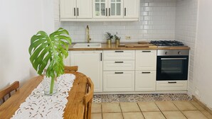 Une cuisine avec des meubles blancs, une cuisinière à gaz, un four et un évier.